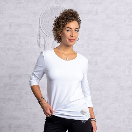 Frau in weißem T-Shirt von The Spirit of OM. Verarbeitet mit einem Faden aus reinem Silber. Silberdruck auf der Hüfte. Ärmel in dreiviertelarm. 