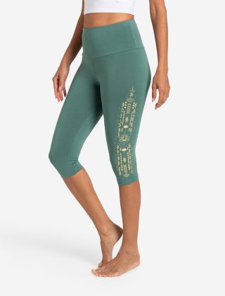 grüne Capri Leggings von The Spirit of OM. Sie hat einen goldenen Ethno-Print auf dem Bein mit einem kleinen Lotus. Hoher Bund. Bio-Baumwolle mit Turmalin. 